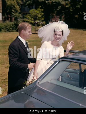 1960 COUPLE jeune mariée et le marié S'EN VOITURE APRÈS LE MARIAGE Banque D'Images