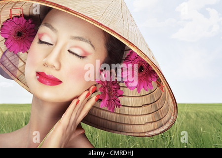 Belle fille vietnamienne dans un chapeau traditionnel est holding Flowers Banque D'Images