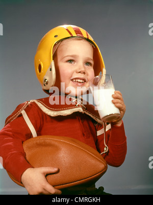 Années 1950 Années 1960 BOY DRINKING GLASS PORTER LAIT FOOTBALL HELMET ÉPAULETTES Banque D'Images