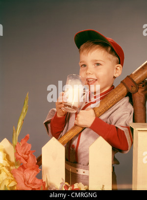 Années 1950 Années 1960 BOY boire du lait portant des uniformes de base-ball par PICKET FENCE Banque D'Images