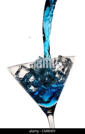 Liqueur bleue a versé dans un verre à cocktail avec des glaçons sur fond blanc Banque D'Images