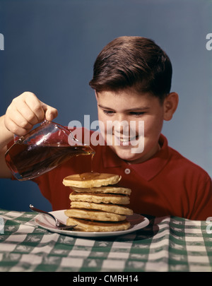 Années 1950 Années 1960 SMILING BOY SUR LE PETIT-DÉJEUNER DE CRÊPES SIROP Banque D'Images