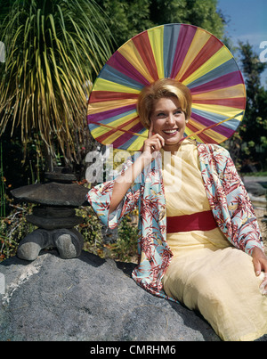 1950 SMILING BLONDE Femme portant des vêtements de style japonais et drôles de couleurs arc-en-ciel SUN HAT Banque D'Images