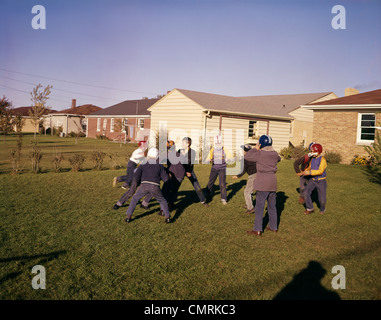 Années 1950 Années 1960 QUARTIER GROUPE GARÇONS JOUER BACKYARD FOOTBALL DE CONTACT MAISONS DE BANLIEUE Banque D'Images