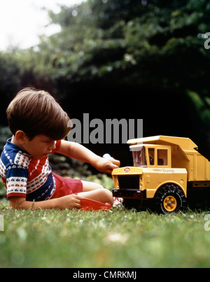 1970 garçon en jouant avec de l'HERBE JAUNE JOUET TONKA DUMP TRUCK Banque D'Images