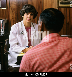 Des années 80, femme médecin INTERROGEANT AFRICAN AMERICAN MALE PATIENT Banque D'Images