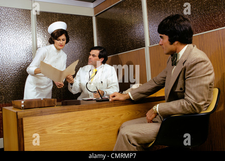 1970 1970 RETRO MAN PATIENT RÉUNION DE BUREAU DUN Médecin Infirmière dossier montrant le tableau pour Médecin Banque D'Images