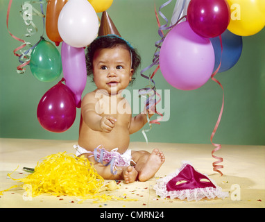 1960 AFRICAN-AMERICAN BABY BOY WEARING PARTY HAT AVEC DES BALLONS de banderoles autour Banque D'Images