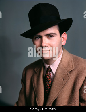 Années 1940 Années 1950 LA MODE PORTRAIT JEUNE HOMME PORTANT CHAPEAU FEDORA noir manteau de poils de chameau et cravate Banque D'Images