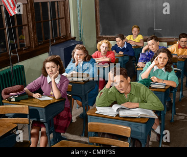 1950 HIGH SCHOOL DE CLASSE D'ENNUYER LES ÉLÈVES ENDORMIS ASSIS À UN BUREAU Banque D'Images