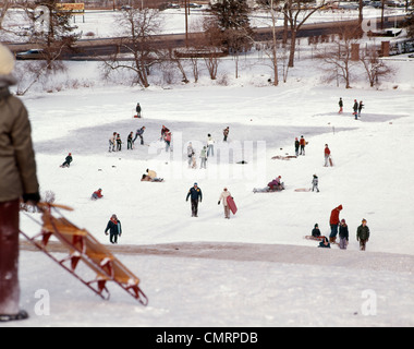 1970 1970 RETRO Enfants jouant au hockey sur étang gelé À PROXIMITÉ DES FAMILLES D'ENFANTS LOISIRS D'HIVER NEIGE TRAÎNEAU À CHIENS Banque D'Images