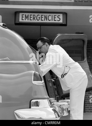 1950 VUE LATÉRALE DU CONDUCTEUR DE L'AMBULANCE EN UNIFORME BLANC AVEC STÉTHOSCOPE DANS L'ouverture de la poche arrière de l'AMBULANCE POUR PRENDRE LES PATIENTS Banque D'Images