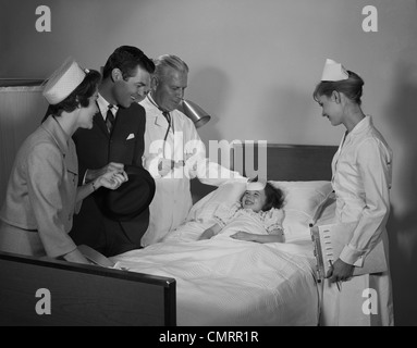 1960 HOMME FEMME Médecin Infirmière Mère Père VISITE PATIENT SMILING LITTLE GIRL IN HOSPITAL BED Banque D'Images