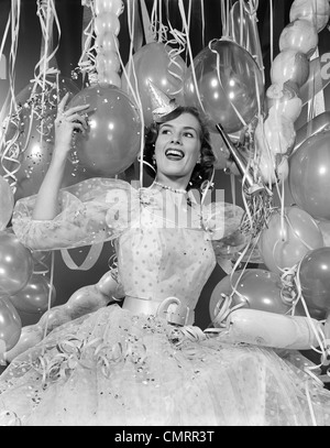 1950 femme en robe de soirée entouré de ballons et de banderoles Banque D'Images