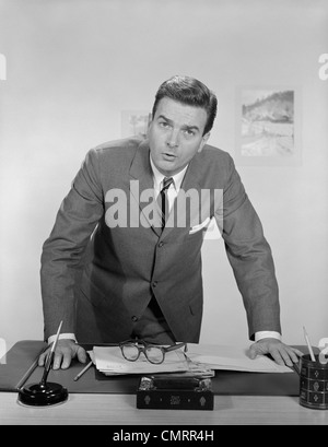 Années 1950 Années 1960 BUSINESSMAN LEANING OVER 24 EXPRESSION GRAVE À L'AVANT Banque D'Images