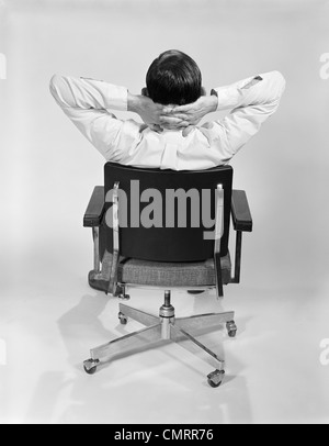 1960 L'HOMME DE DERRIÈRE LE BUREAU DE LA PRÉSIDENCE DE SÉANCE DANS LES MAINS JOINTES derrière la nuque Banque D'Images