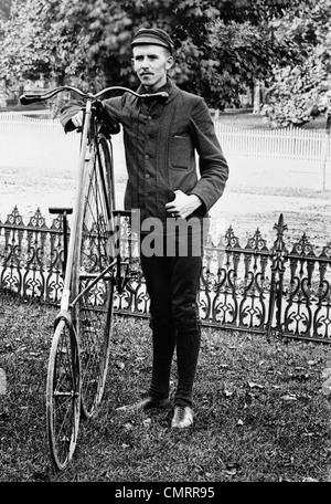 Années 1880 Années 1890 homme appelé , PORTANT DES VÊTEMENTS POUR L'équitation de vélo debout à côté d'un CLIQUET ROUE LOCATION Banque D'Images