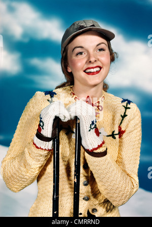 Années 1940 Années 1950 PORTRAIT SMILING WOMAN WEARING WINTER SWEATER ET DES GANTS QUI S'APPUYANT SUR SKIS Banque D'Images