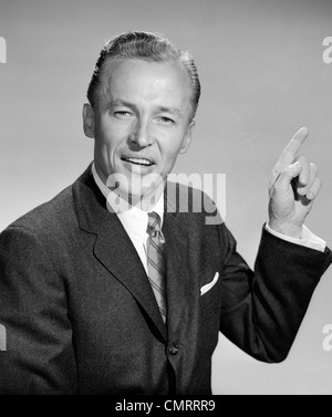 1950 BUSINESS MAN POINTING WITH MAIN GAUCHE EXPRESSION INTERROGATEUR LOOKING AT CAMERA Banque D'Images