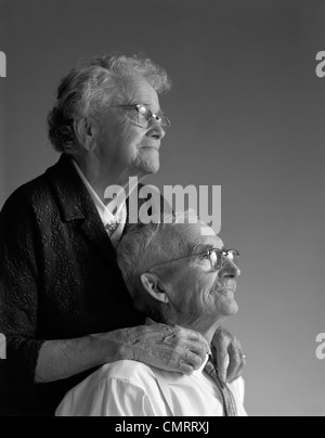 1960 PORTRAIT DE COUPLE DE PERSONNES ÂGÉES DANS LEUR 80s Temps PORTÉS MAINS TOUCHANT STUDIO Banque D'Images