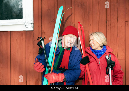 Deux personnes âgées debout à l'extérieur avec leurs skis Banque D'Images