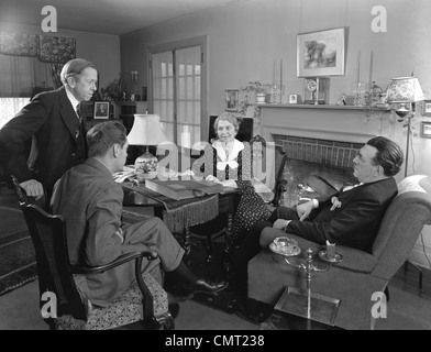 Années 1930 Années 1940 DEUX VENDEURS RÉALISENT DES VENTES PRÉSENTATION AU VIEUX COUPLE MARI ET FEMME ASSIS DANS LA SALLE DE SÉJOUR Banque D'Images