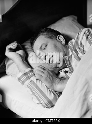 Années 1940 Années 1950 HOMME ENDORMI SLEEPING IN BED WEARING PAJAMAS Banque D'Images