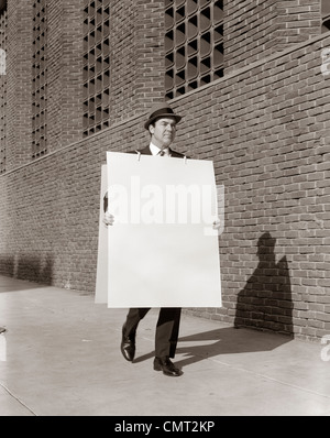 1950 BUSINESSMAN WALKING TROTTOIR PORTANT CONSEIL SANDWICH PUBLICITÉ Banque D'Images