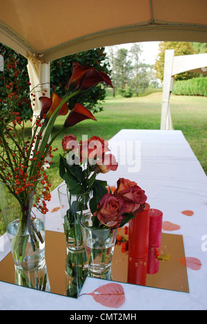 Gazebo de mariage blanc avec des fleurs rouges et des bougies décoration dans un jardin Banque D'Images