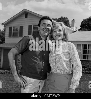 1960 Heureux COUPLE PORTRAIT MAN WOMAN SMILING IN FRONT OF HOME Banque D'Images