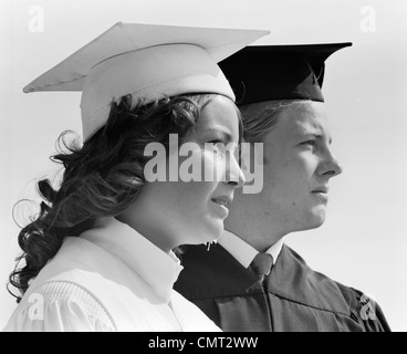 Années 1970, close-up DE DEUX DIPLÔMÉS EN CAP & robe de chambre homme EN NOIR & BLANC EN FEMELLE À DISTANCE EN OFF Banque D'Images