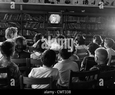 1950 VUE ARRIÈRE DE LA BIBLIOTHÈQUE DE L'ÉCOLE LES ENFANTS DE REGARDER LA TÉLÉVISION ÉCRAN Banque D'Images