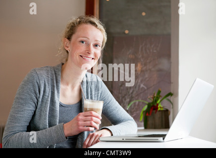 Femme ayant une tasse de café en face de l'ordinateur portable Banque D'Images