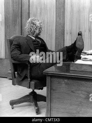 1930 HOMME DE PAILLE EN LITIGE ET CRAVATE ASSIS DANS LA CHAISE avec pieds posés sur Office 24 Banque D'Images