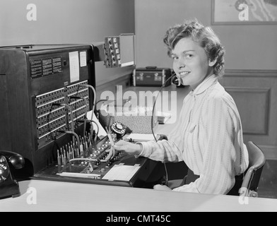 1950 SMILING WOMAN AU BUREAU TÉLÉPHONE STANDARDISTE Banque D'Images