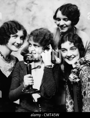 Années 20, groupe de quatre femmes réunies autour de CANDLESTICK PHONE Banque D'Images