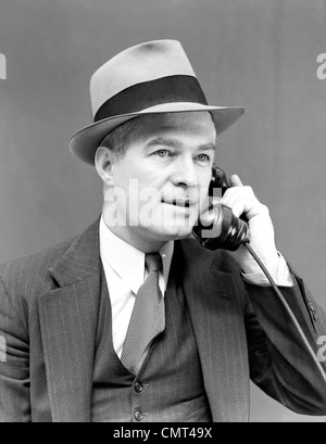 1930 1940 MAN WEARING HAT & Costume Cravate et veste en conversation sur téléphone EXPRESSION GRAVE MAN PORTRAIT Banque D'Images