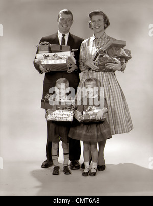 1960 Portrait de famille de quatre mère père Garçon Fille CARRYING CHRISTMAS GIFTS GIFTS Banque D'Images