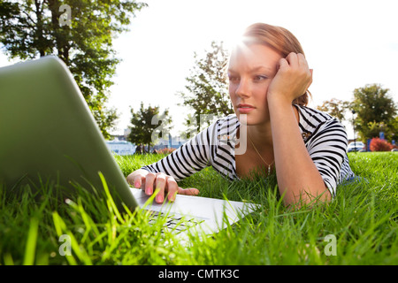 Woman lying on grass while using laptop Banque D'Images
