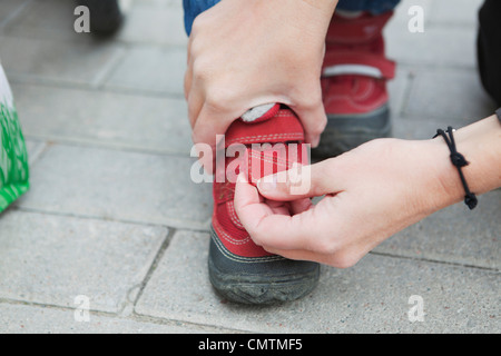 Close-up of mother helping daughter (2-3) à mettre sur ses chaussures Banque D'Images