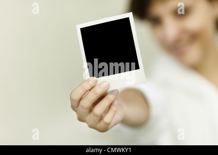 Jeune femme tenir blank photo, selective focus on foreground Banque D'Images