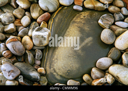 Porter l'eau sur la plage de galets qui entourent un plus grand rock Banque D'Images