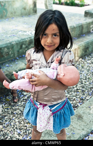 Petit sourire timide fille indienne mexicaine autochtone avec croûte sur front timidement la tient pour poupée en plastique réaliste Oaxaca Banque D'Images