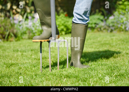 Femme aérant le jardin pelouse avec une fourche d'excavation Banque D'Images