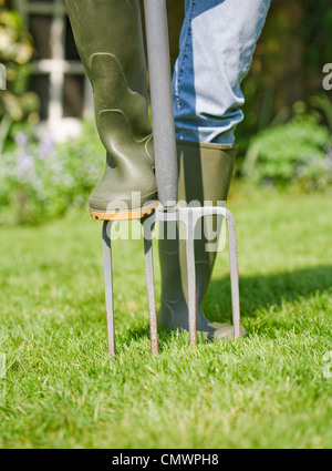 Femme aère jardinier jardin pelouse avec une fourchette Banque D'Images