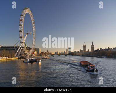 Le London Eye illuminée par un coucher de soleil Tamise barge et de travail en aval navigation Chambres du Parlement London UK Banque D'Images