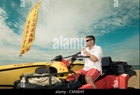 Lifeguard assis sur quad avec canoë et d'un drapeau à patrouiller beach Banque D'Images