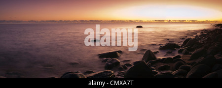 L'aube sur la mer de Corail à une plage de galets, près de Cairns, Queensland, Australie Banque D'Images