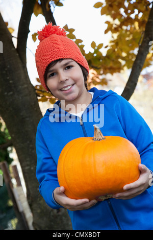 Allemagne, Huglfing, Boy holding pumpkin, smiling, portrait Banque D'Images