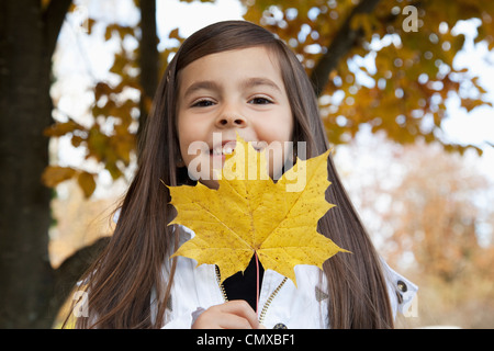 Allemagne, Huglfing, Girl holding leaf, smiling, portrait Banque D'Images